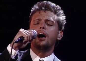 Descubre la lujosa casa de un famoso cantante: secretos y detalles exclusivos en una imagen que muestra a un intérprete masculino cantando apasionadamente con micrófono y traje formal.