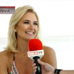 Mujer rubia sonriente durante una entrevista con un micrófono rojo de ¡HOLA! TV y rótulo 'EXCLUSIVA'.