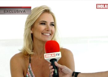 Mujer rubia sonriente durante una entrevista con un micrófono rojo de ¡HOLA! TV y rótulo 'EXCLUSIVA'.