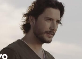 Hombre adulto con barba y cabello oscuro mirando al horizonte en primer plano.