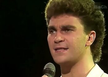 Hombre joven en primer plano cantando con micrófono en escenario, expresión intensa — Las parejas de Lucero: descubre sus romances más icónicos