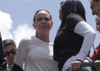 La familia de María Corina Machado: historia y legado inspirador, grupo de personas en un acto público al aire libre con una mujer en primer plano y otras personas conversando.