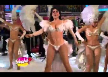 Bailarina en traje blanco y plumas realizando una coreografía en un escenario