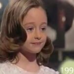 Niña con vestido blanco y peinado vintage frente a un escenario con luces, ¿Qué fue de Raulito? Descubre su sorprendente transformación actual