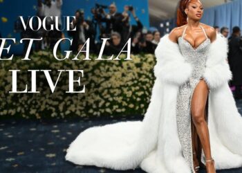 Mujer con vestido plateado y abrigo de piel blanco en la alfombra roja del Met Gala mostrando una llamativa melena rojiza