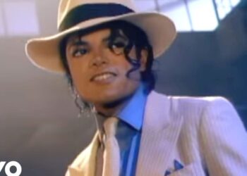 Hombre con sombrero blanco y traje elegante sonriendo en un escenario