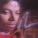 El legado financiero de Michael Jackson: ¿cómo se reparte su fortuna? 7 Retrato en primer plano de un hombre joven con cabello rizado y expresión pensativa frente a un muro de ladrillo, estética retro y iluminación suave.