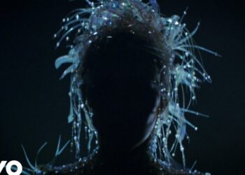 Silueta en penumbra con un tocado brillante y hebras luminosas que crean un efecto etéreo y detallado.