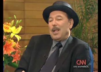 Hombre con sombrero y traje sentado en una entrevista televisiva con arreglo floral y logotipo de CNN en Español.