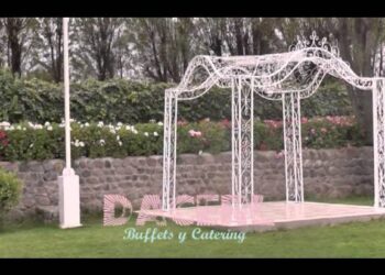 Pérgola blanca ornamental sobre césped con muro de piedra y flores en el jardín — La casa de Gisela: secretos y curiosidades que no conocías