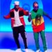 El patrimonio de Nicky Jam: secretos y negocios revelados 21 Imagen de dos artistas urbanos bailando en un set iluminado en azul, portada para El patrimonio de Nicky Jam: secretos y negocios revelados.