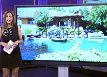 Presentadora de televisión en un plató junto a una gran pantalla que muestra una casa con piscina y jardines - Dónde vive Irene Montero: descubre su hogar en Galapagar