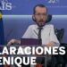 Político en silla de ruedas en un atril con banderas y micrófonos, rueda de prensa sobre declaraciones y patrimonio.