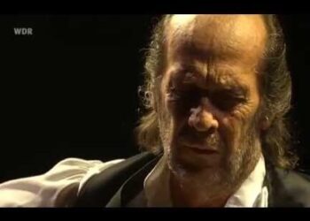 Guitarrista flamenco en primer plano con luz cálida y rostro concentrado, evocando raíces en Algeciras y un profundo legado flamenco.