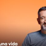 Retrato de un profesional de la medicina sonriendo sobre un fondo naranja; no es posible identificar a la persona en la imagen.