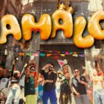 Grupo de personas bailando en una calle festiva con grandes letras amarillas en el fondo; Poncho de Nigris: Descubre cuántos hijos tiene y su historia familiar