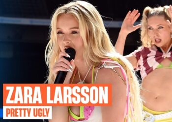 Cantante rubia en primer plano con micrófono y top veraniego en una actuación en vivo