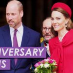 Descubre el encantador secreto de la noche de aniversario que te dejará sin aliento: una elegante pareja real sonriente, ella con abrigo rojo y ramo de flores, él con traje azul.