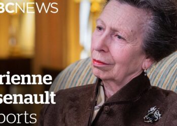 Descubre la sorprendente razón por la que esta mujer se viste diferente en Trooping the Colour, retrato de mujer mayor sentada con chaqueta marrón, broche y pendientes de perla
