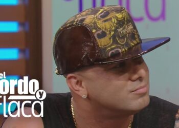 Hombre con gorra estampada y accesorios dorados en una entrevista televisiva en primer plano; no es posible identificar a la persona
