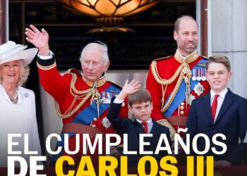 Balcón con el monarca y su familia en uniforme ceremonial saludando durante una celebración pública.