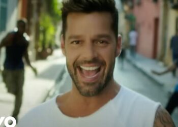 Hombre sonriente en primer plano en una calle colorida, expresión alegre y energía veraniega.