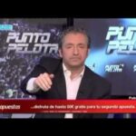 Presentador de programa deportivo en plató con rótulos luminosos y gesto serio, ambiente de debate televisivo