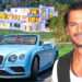 Hombre sonriente junto a un coche deportivo convertible azul y una mansión de lujo