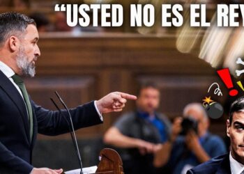 Orador serio señalando con el dedo frente a un micrófono en un hemiciclo