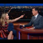 Actriz sonriente en un programa nocturno señala al presentador en una sorprendente foto que no te querrás perder tras el anuncio del embarazo.