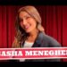 Sonrisa y mirada directa de sasha meneghel frente a cortinas rojas