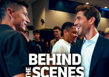 Dos hombres conversando en un evento con público y un gran rótulo 'BEHIND THE SCENES'; ¿Cuánto cobra Sergi Roberto? Descubre su salario actual y más