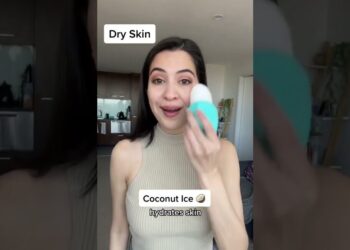 Mujer sosteniendo un dispositivo facial azul y blanco para piel seca con rótulos 'Dry Skin' y 'Coconut Ice hydrates skin'.