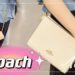 Mujer sostiene dos bolsos Coach crossbody, uno crema con cadena dorada y otro de monograma marrón; Descubre por qué esta bolsa de Coach de $250 ahora cuesta solo $75 y todos la consideran ‘perfecta’.