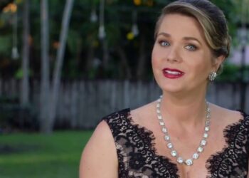 Mujer elegante con vestido negro de encaje y collar brillante posando al aire libre; identidad no identificable