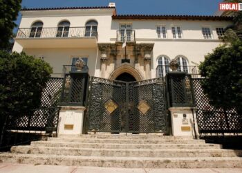 La casa de Versace: descubre el lujo y la historia de su mansión con un portón ornamental de hierro y escalones de piedra frente a una fachada mediterránea.