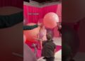Modelo sentada en una sesión fotográfica con vestido rosa de plumas, grandes globos y equipo de producción en un set rosa