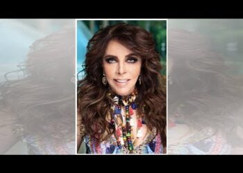 Retrato de una mujer adulta con cabello largo y ondulado, maquillaje marcado y collares coloridos.