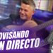 Hombre sonriente tocando guitarra en un plató morado con un micrófono vintage y el rótulo "Improvisando en directo".
