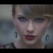 Primer plano de una cantante con maquillaje dramático, labios rojos brillantes y pendientes colgantes que resaltan una mirada intensa