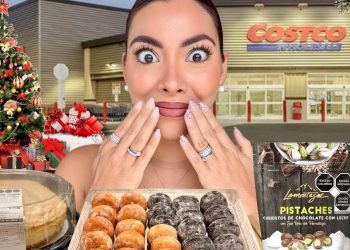 Descubre los 7 pueblos galeses más encantadores para unas vacaciones festivas, ¡uno de ellos tiene fogata en la playa! Mujer sorprendida frente a una tienda con árbol de Navidad, regalos, tarta, bandeja de donuts, pistachos cubiertos de chocolate y botella de eggnog