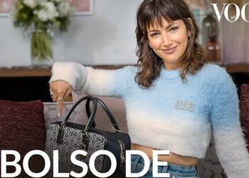 Actriz sonriente en un sofá señalando un bolso de lujo en una portada de revista, estilo editorial y moda