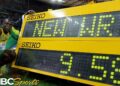 Atleta jamaiquino celebrando junto a un marcador amarillo que anuncia nuevo récord y tiempo de 9.58 tras una carrera histórica.