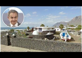 Casa costera de lujo con muros de piedra volcánica, domos blancos y embarcación en tierra frente al mar