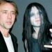 Los secretos de los hijos de Nicolas Cage: ¿Quiénes son y qué hacen? Imagen con dos personas: un hombre de rostro maduro con chaqueta oscura y otra persona de estilo gótico con maquillaje pálido, cabello largo y gesto rockero.