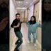 Dos personas en un pasillo de hotel o edificio, levantando las manos como si bailaran o posaran para un video