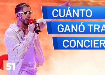 Cantante en escenario con micrófono rojo y gafas, ¿Cuánto cobra este artista por concierto? Descubre su increíble sueldo