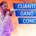 Cantante en escenario con micrófono rojo y gafas, ¿Cuánto cobra este artista por concierto? Descubre su increíble sueldo