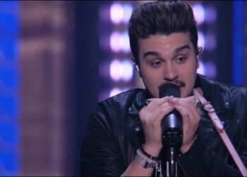 Cantante masculino con chaqueta de cuero sosteniendo un micrófono en el escenario