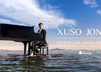 Hombre con traje sentado al piano de cola sobre el agua en una imagen promocional con cielo despejado y texto grande en la composición